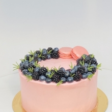 Праздничный нежно розовый торт декорированный ароматными ягодами ежевики и голубики и печенками макаронс.