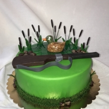 Торт праздничный, выполненный в виде водоёма с камышами, уточкой и ружьём охотника,заказать недорого в Минске.