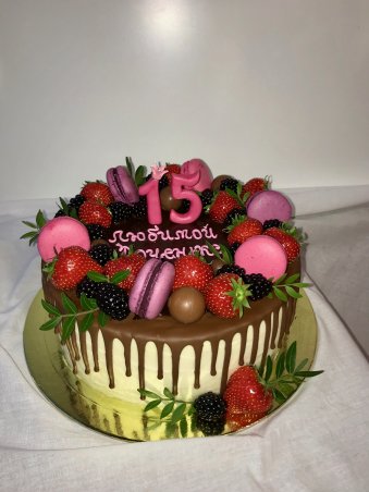 Торт детский круглой формы покрытый кремом декорированный шоколадом и свежими ягодами.