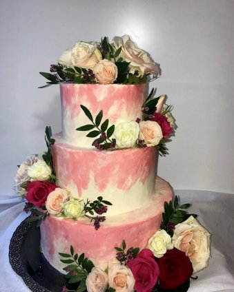 Торт трехъярусный на свадьбу, украшен цветами в нежно-розовом и белом цвете.