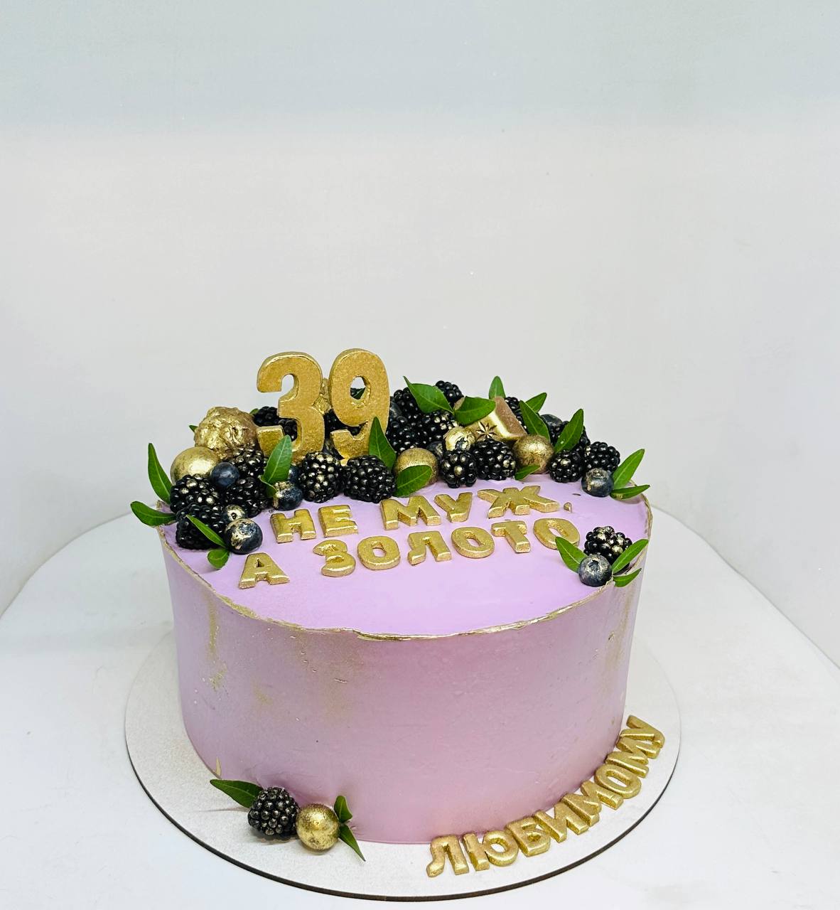 Торт праздничный белоснежный, покрыт кремом и украшен ягодами  голубики и веточками розмарина.